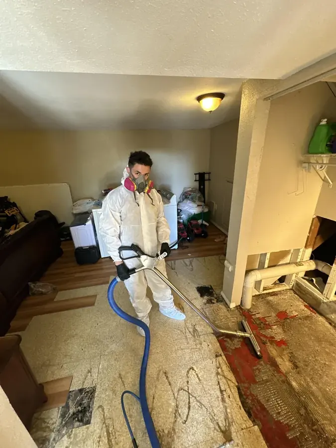Technician in protective gear cleaning a sewage backup in a Peyton, CO home